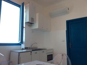 a kitchen with a sink and a table and a door at Blue Apartment in Sanremo