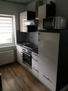 eine Küche mit weißen Schränken, einem Herd und einem Fenster in der Unterkunft Ferienwohnung in Neunkirchen