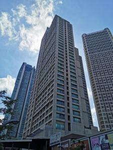 a tall building in a city with two tall buildings at N place at Soho Central in Manila