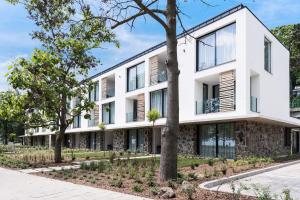 una vista exterior de un edificio blanco con árboles en OliverLux Aparthotel, en Tihany