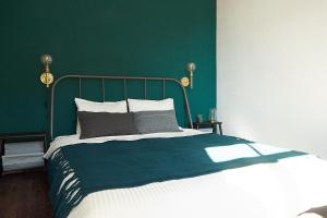 a bedroom with a bed with a green wall at Greenhouse Apartments in Jūrmala