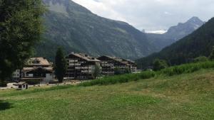 a group of buildings on a hill with mountains at Condominio Colmet in La Thuile