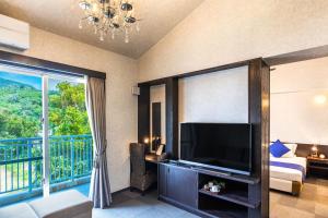 a living room with a television and a balcony at Kerama Terrace in Tokashiki