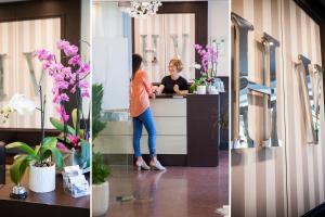 une femme debout à un comptoir dans une pièce avec des fleurs dans l'établissement Hotel Virginia, à Diano Marina