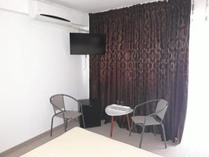 um quarto com duas cadeiras, uma mesa e uma cortina em Vila Cristian em Eforie Nord
