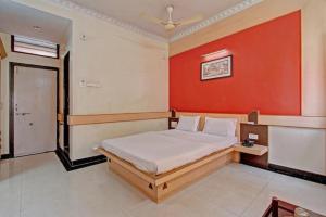 a bedroom with a bed with a red wall at Bharati Lodge in Hubli
