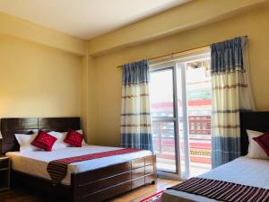 a bedroom with two beds and a large window at Hotel Lilyland Pvt Ltd in Pokhara