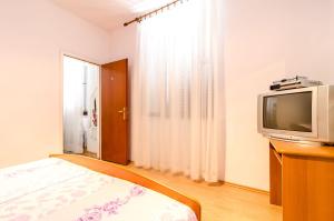 a bedroom with a bed and a tv and a window at Rooms Mozara in Trsteno