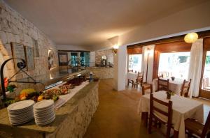 a kitchen and dining room with a table and chairs at Hotel Club Can Jordi in Cala Llenya