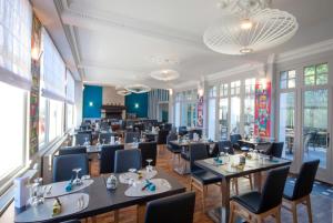 - une salle à manger avec des tables, des chaises et des fenêtres dans l'établissement Logis - Hostellerie & Restaurant du Marché, à Le Cateau