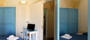オートラントにあるOtranto Vacanza Facile - La Corteの青いキャビネット、テレビ、鏡が備わるベッドルーム1室