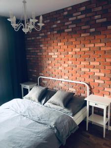 Un dormitorio con una pared de ladrillo y una cama en Lofty & Apartamenty Garnizon Gdańsk en Gdansk