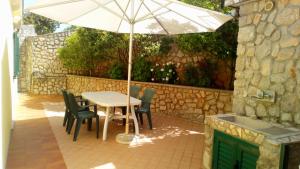 - une table et des chaises avec un parasol sur la terrasse dans l'établissement Apartmani Valentina, à Veli Lošinj
