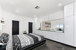 um quarto branco com uma cama em preto e branco e um lavatório em KENNEDY EXECUTIVE TOWNHOUSE em Mount Gambier