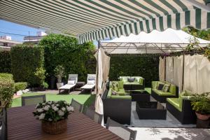 un patio con mobili verdi sotto una tettoia a righe di New Opening Villa Oasis Terramar a Sitges