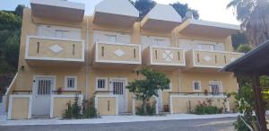 a large yellow building with white doors and windows at Denise Apartments in Kefalos