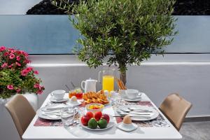a table with a breakfast of eggs and fruit at Irene City Villas in Fira