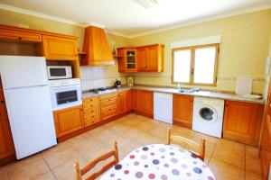cocina con armarios de madera y nevera blanca en Marques - holiday home with private swimming pool in Benitachell, en Benitachell