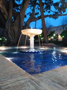 a fountain in the middle of a pool at night at APARTAMENTO APODACA in Cádiz