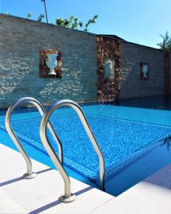 ein Pool mit zwei Metallschienen neben einer Ziegelwand in der Unterkunft Aleppo Hotel in Yerevan