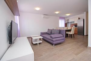 a living room with a purple couch and a table at Apartments Smojver Stipe in Baška