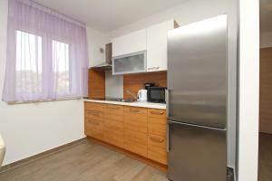 una cocina con nevera de acero inoxidable y armarios de madera en Apartments Smojver Stipe en Baška