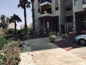 a car parked in front of a building with palm trees at 2 BDR Nitza appartment with balkony in Netanya