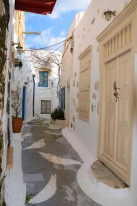 a narrow alley with white buildings and a door at Kleio House in Astypalaia Town