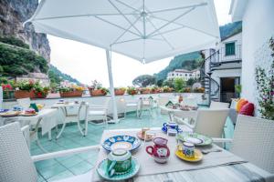 een tafel met borden eten op een balkon met een parasol bij Valle d'Amalfi Suites in Amalfi