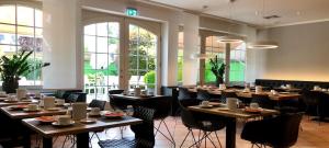 a dining room with tables and chairs and windows at Hotel Sonderfeld in Grevenbroich