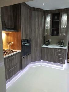 a kitchen with wooden cabinets and a white floor at Home Away From Home in Port Elizabeth