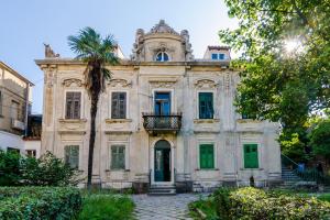 uma casa velha com uma palmeira em frente em Villa Roma em Dubrovnik