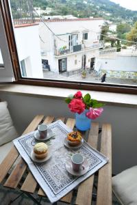Una mesa con dos tazas de café y flores. en Luna Caprese Guest House en Anacapri