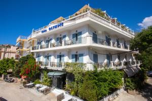 a white building with balconies on a street at Olympic Hotel in Parga