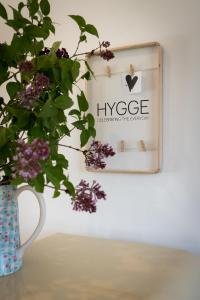 un jarrón con una planta en una mesa con un cartel en Gästehaus hygge, en Nübbel