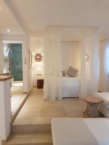 a white bedroom with a bed with white curtains at Kavos Hotel Naxos in Agios Prokopios