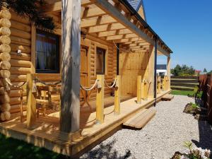 a log cabin with a porch and a bench at BeHappy Woodhouse in Jastrzębia Góra