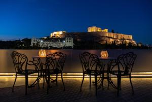 una mesa y sillas en un balcón por la noche en Acropolis View Hotel, en Atenas