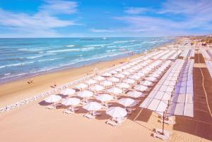 a beach with many white umbrellas and the ocean at Alean Family Resort & SPA Riviera 4* Ultra All Inclusive in Anapa