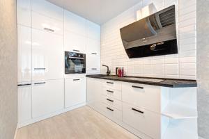 a white kitchen with white cabinets and a microwave at Apartment Voskresenska 18 , Парковые Озера in Kyiv