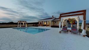 a swimming pool with two chairs and a gazebo at Villa Melody Novalja in Novalja