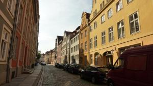 een straat met auto's geparkeerd op een geplaveide straat bij Altstadt Pension Hafenblick in Stralsund