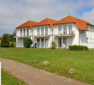 ein großes weißes Haus mit orangefarbenem Dach in der Unterkunft Ferienapartment Wiese & Meer auf Rügen in Neddesitz