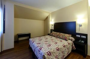 a bedroom with a bed with a floral bedspread at Hotel Restaurante La Peseta in Astorga