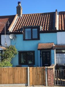 a blue house with a wooden fence in front of it at Turning Tides Holiday Cottage in Great Yarmouth