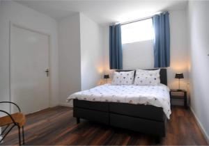 een slaapkamer met een bed en een raam met blauwe gordijnen bij De Tol Tolkamer in Tolkamer
