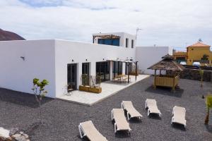 a group of chaise lounges in front of a house at MAAR House Lajares in Lajares
