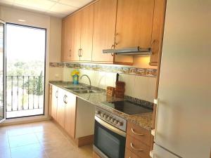 a kitchen with wooden cabinets and a sink and a stove at Apartamento exterior en La Ametlla de Mar in L'Ametlla de Mar