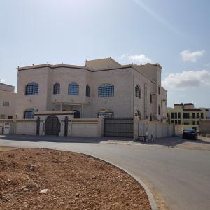 a large white building with a fence in front of it at Alarbee Aljeded in Salalah