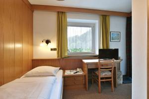 a bedroom with a bed and a desk with a computer at Hotel Garni Vanadis in Ortisei